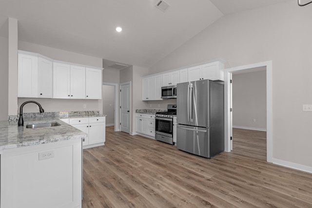 kitchen featuring visible vents, light wood-type flooring, white cabinets, stainless steel appliances, and a sink