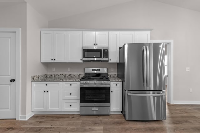 kitchen featuring stainless steel appliances, lofted ceiling, white cabinets, and light wood finished floors