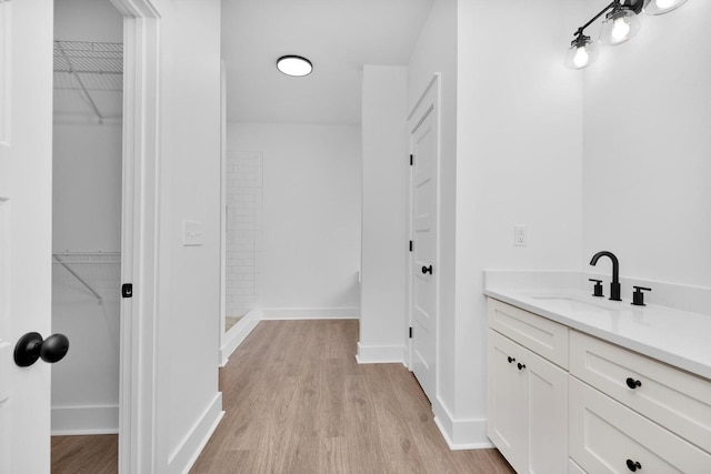 bathroom featuring a spacious closet, vanity, and wood finished floors