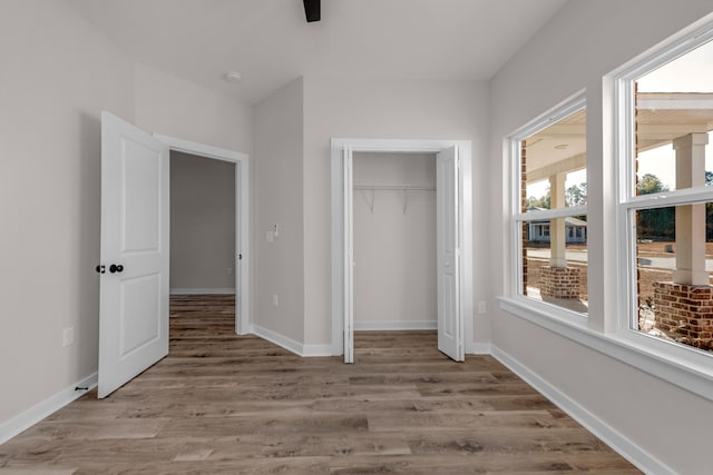 unfurnished bedroom featuring wood finished floors, baseboards, and a closet