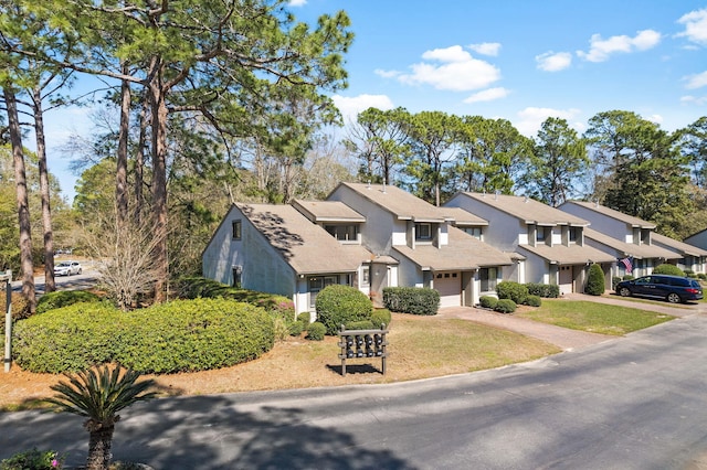 view of front of property featuring stucco siding, driveway, a residential view, a front yard, and a garage