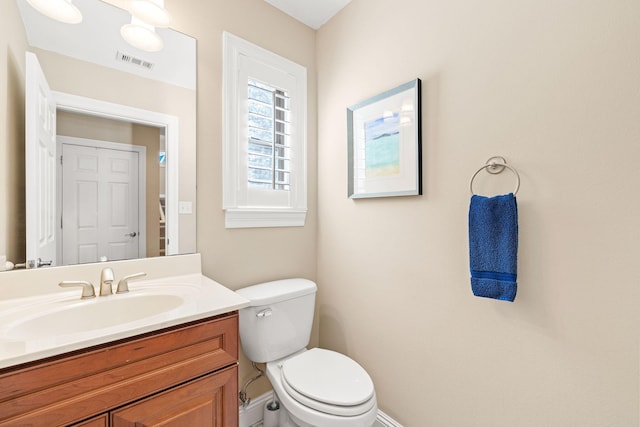 half bath with visible vents, toilet, vanity, and baseboards