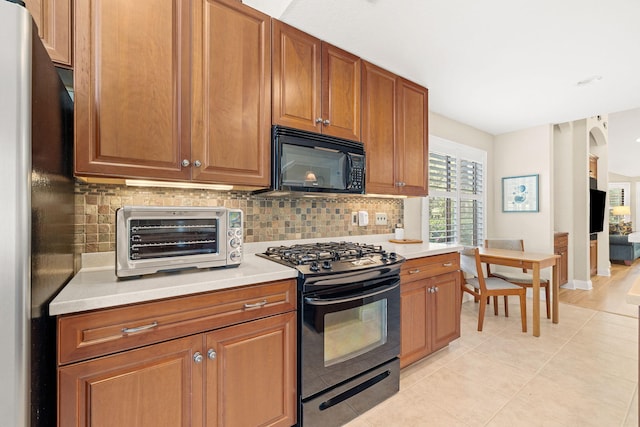 kitchen with tasteful backsplash, black appliances, light countertops, and a toaster