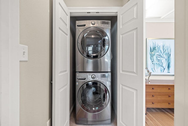 clothes washing area with laundry area, wood finished floors, and stacked washer / drying machine