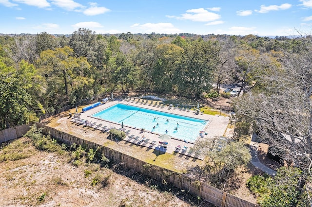 pool with a patio area, a view of trees, and fence