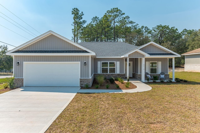 craftsman house featuring driveway, a shingled roof, covered porch, an attached garage, and a front yard