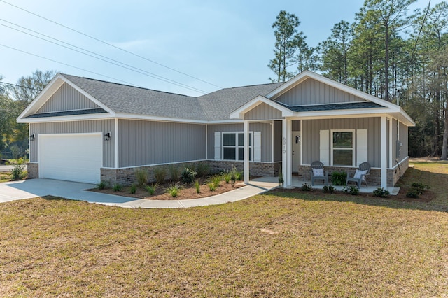 view of front facade with a front yard, covered porch, an attached garage, and a shingled roof