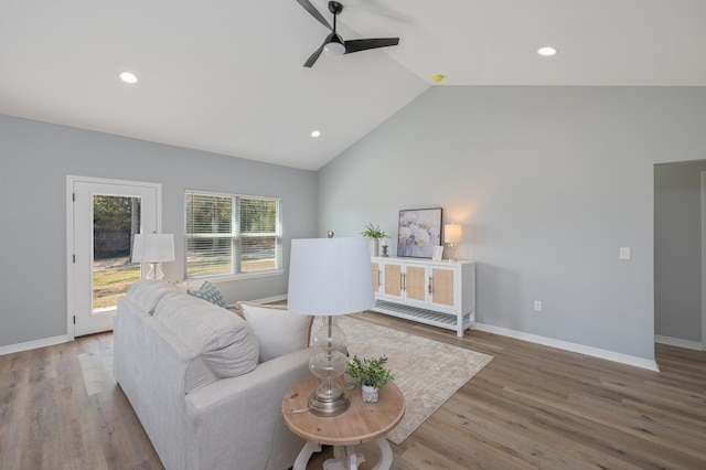 living area with baseboards, a ceiling fan, lofted ceiling, and wood finished floors