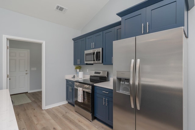 kitchen featuring visible vents, blue cabinetry, appliances with stainless steel finishes, light countertops, and lofted ceiling