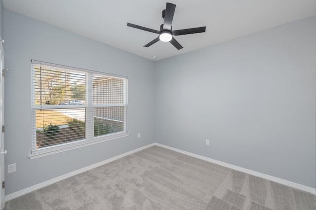 carpeted empty room featuring a ceiling fan and baseboards