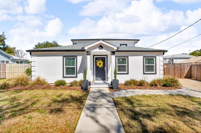 bungalow with stucco siding, a front yard, and fence