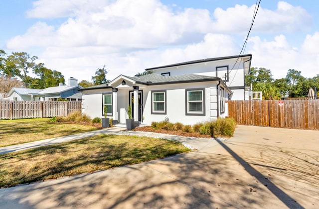 view of front of property featuring a front lawn, fence, and stucco siding