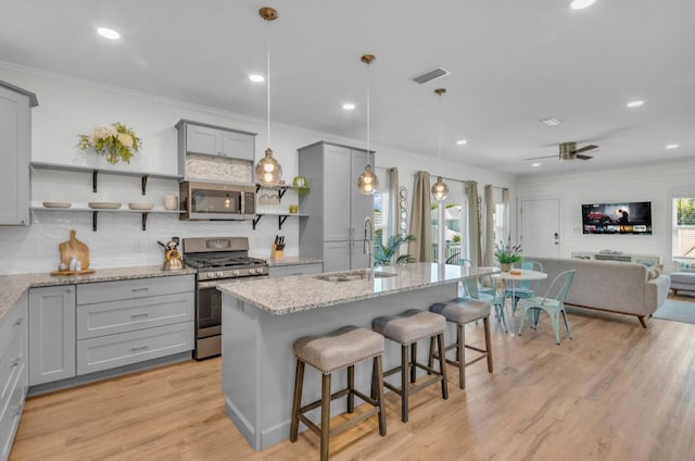 kitchen with visible vents, open shelves, gray cabinetry, a sink, and appliances with stainless steel finishes