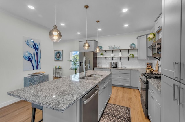 kitchen featuring light wood-type flooring, open shelves, a sink, appliances with stainless steel finishes, and tasteful backsplash