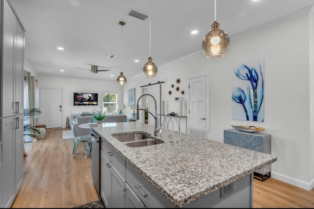 kitchen with visible vents, a sink, gray cabinetry, a barn door, and stainless steel dishwasher