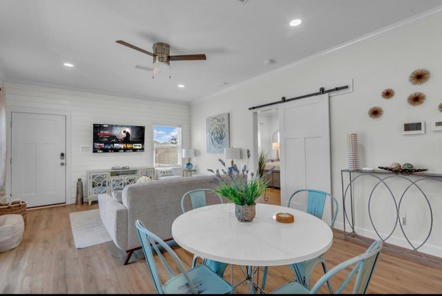 dining room with light wood-style flooring, a ceiling fan, recessed lighting, a barn door, and crown molding