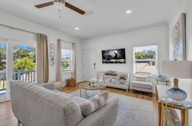 living room with recessed lighting, visible vents, wood finished floors, and ornamental molding