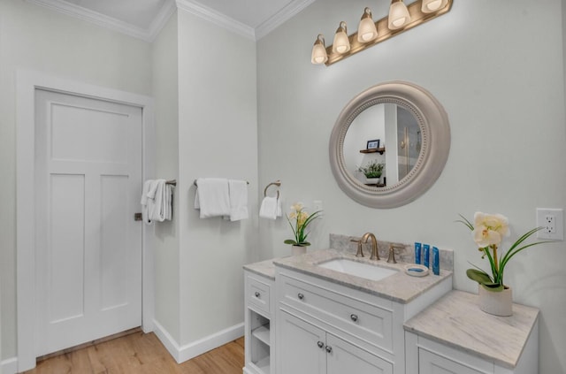 bathroom with vanity, crown molding, wood finished floors, and baseboards