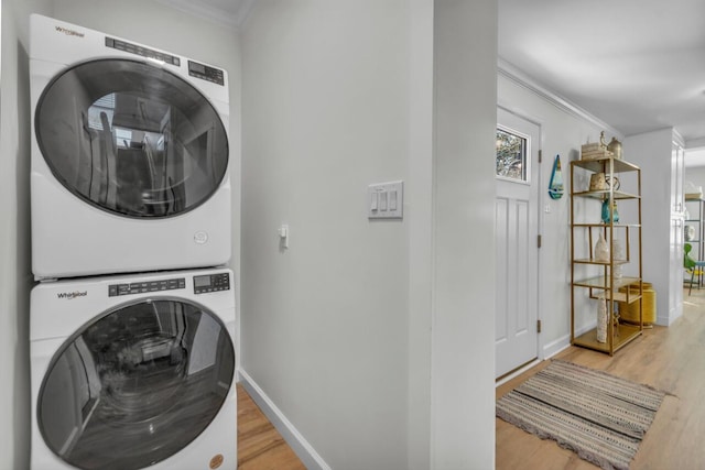 laundry room with stacked washer / dryer, laundry area, light wood-type flooring, and ornamental molding