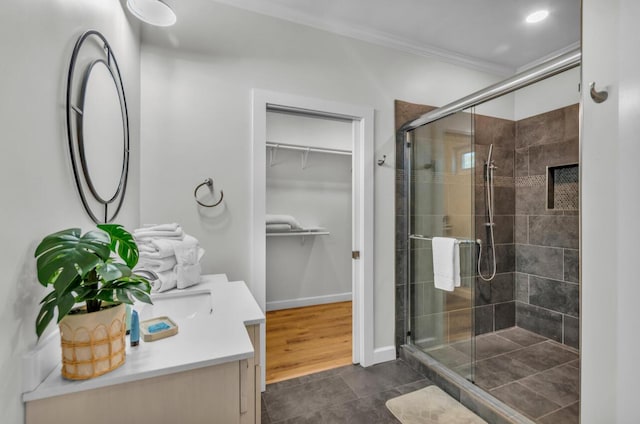 full bath featuring vanity, baseboards, a stall shower, ornamental molding, and a walk in closet