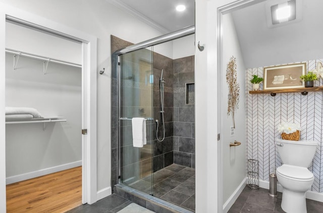 full bathroom featuring a spacious closet, a shower stall, toilet, and baseboards