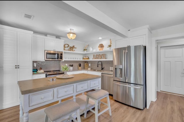 kitchen with visible vents, open shelves, a sink, stainless steel appliances, and decorative backsplash