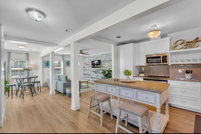 kitchen with light wood finished floors, stainless steel appliances, decorative backsplash, white cabinets, and butcher block counters