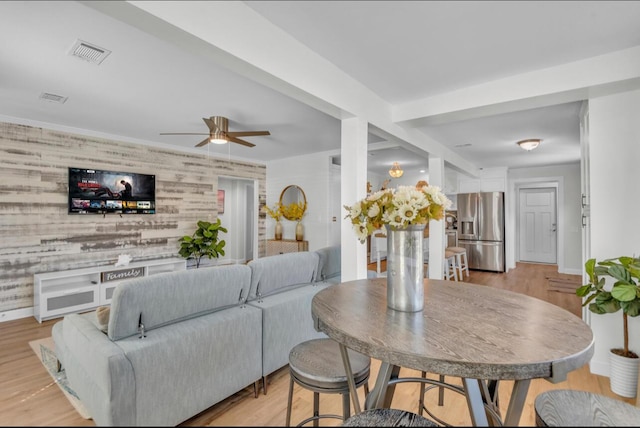 living area with light wood finished floors, visible vents, ceiling fan, and baseboards