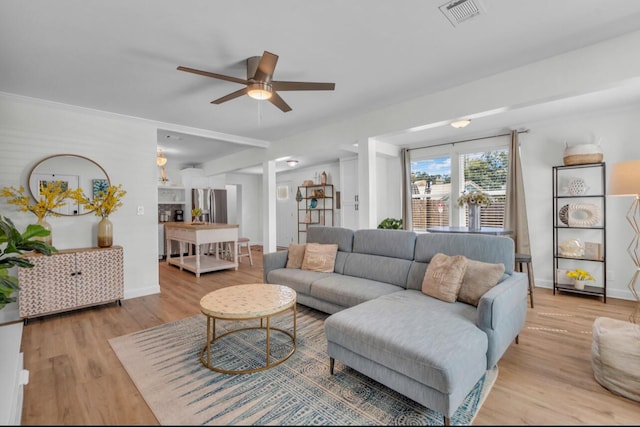 living area featuring visible vents, baseboards, light wood-type flooring, and a ceiling fan