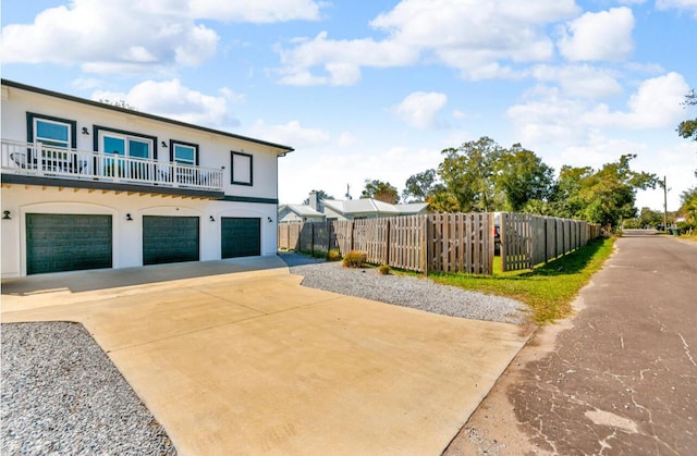 view of front facade with a garage, stucco siding, driveway, and fence