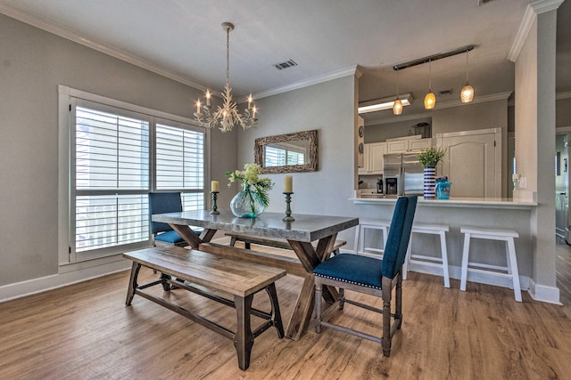 dining room with visible vents, an inviting chandelier, wood finished floors, and ornamental molding