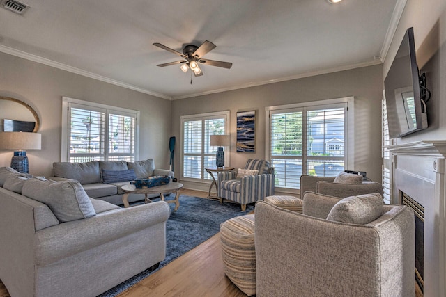 living area featuring visible vents, wood finished floors, a ceiling fan, and ornamental molding