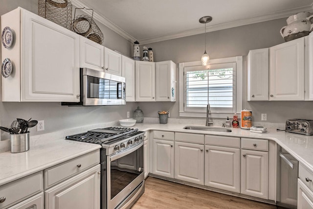 kitchen featuring a sink, stainless steel appliances, light countertops, white cabinetry, and crown molding