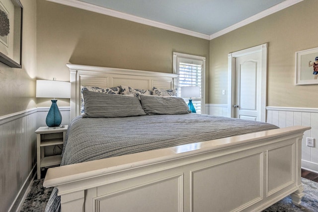 bedroom with dark wood finished floors, ornamental molding, and wainscoting