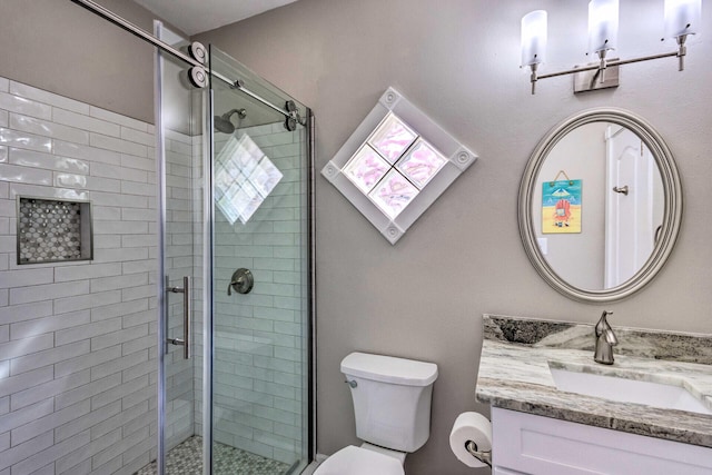 full bathroom featuring a shower stall, toilet, and vanity