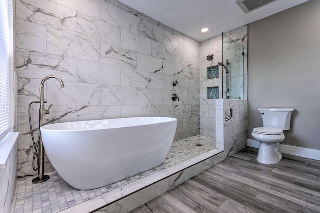 full bathroom with visible vents, a freestanding bath, toilet, a tile shower, and wood finished floors