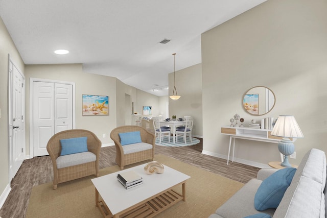 living room featuring lofted ceiling, wood finished floors, visible vents, and baseboards