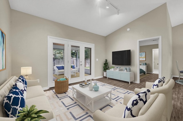 living area with vaulted ceiling, wood finished floors, baseboards, and french doors