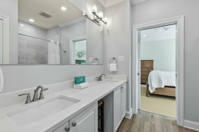 bathroom featuring a sink, visible vents, wood finished floors, and ornamental molding