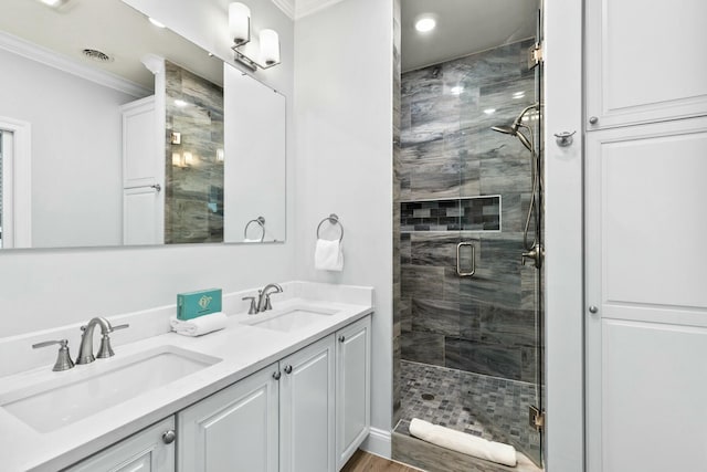 full bathroom with crown molding, visible vents, a shower stall, and a sink