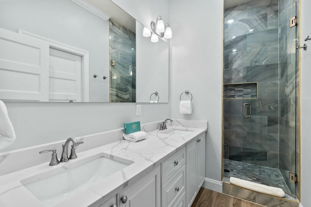 bathroom featuring a shower stall, wood finished floors, double vanity, and a sink