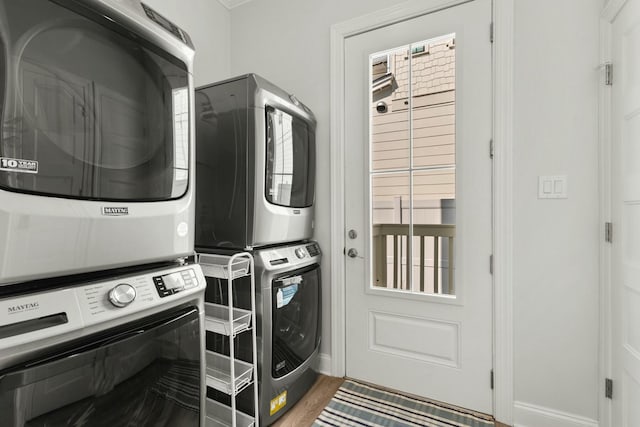 laundry area with laundry area, baseboards, and stacked washer / drying machine