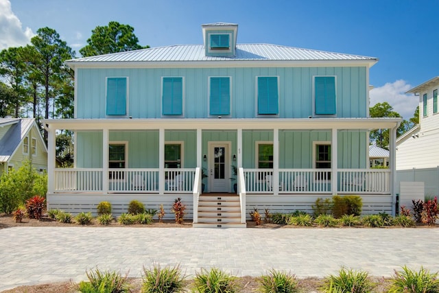 view of front facade featuring covered porch, board and batten siding, and metal roof