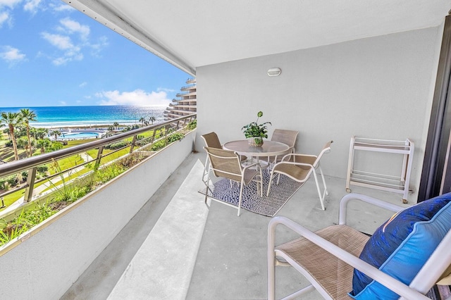 balcony with a water view, a sunroom, and a beach view