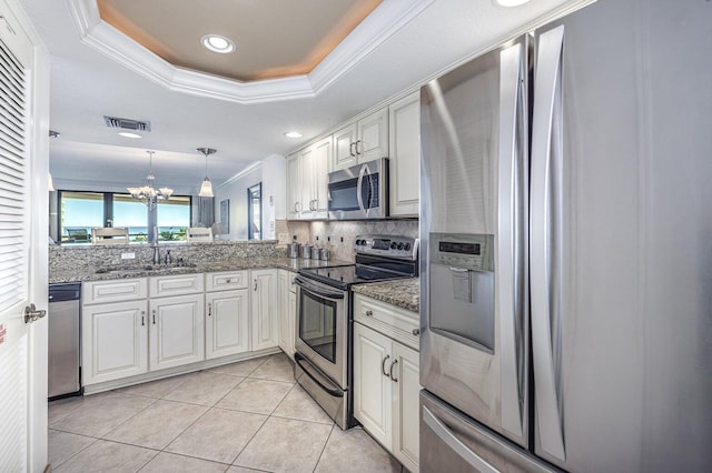 kitchen with visible vents, crown molding, a tray ceiling, stainless steel appliances, and a sink