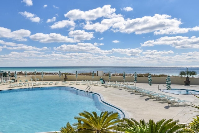 pool featuring a patio area, fence, and a water view