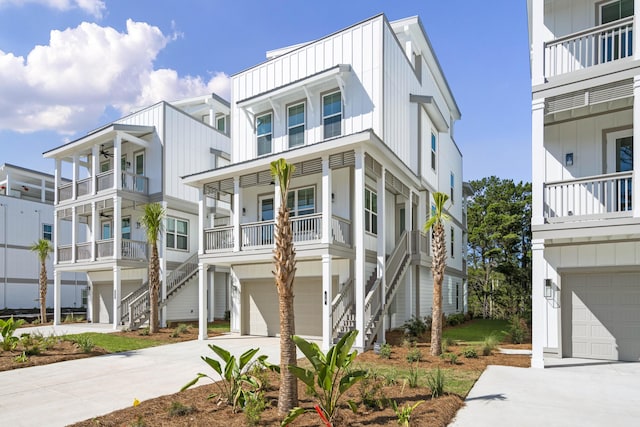 coastal home with concrete driveway, an attached garage, board and batten siding, and a residential view