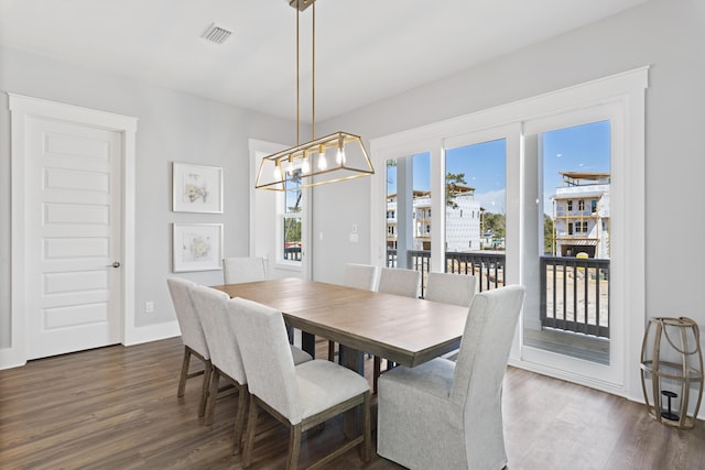 dining space with dark wood finished floors, visible vents, baseboards, and an inviting chandelier