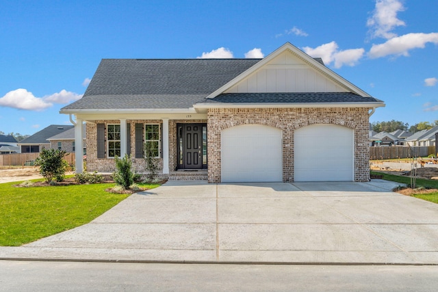 view of front of property featuring a front yard, roof with shingles, an attached garage, concrete driveway, and brick siding