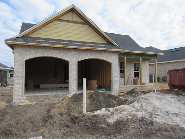 exterior space with an attached garage, brick siding, and a shingled roof